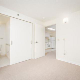 A minimalist apartment interior with white walls and carpeted flooring.