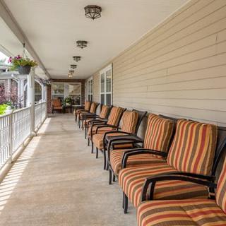 A long porch with a row of chairs featuring striped cushions, offering inviting outdoor seating.