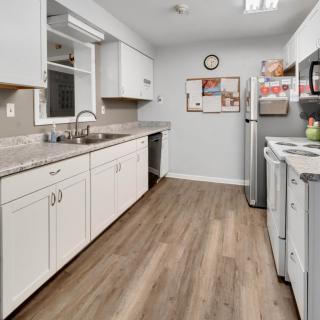 A modern kitchen with white cabinets and wood flooring.