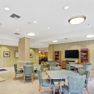 A community room with tables, chairs, a television, and bookshelves.