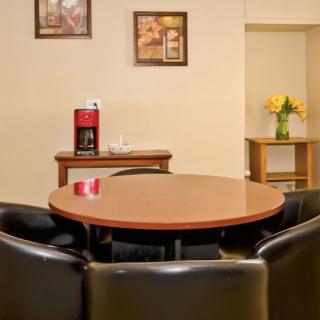 A cozy room with a round table and chairs, featuring a coffee maker and decorative artwork.