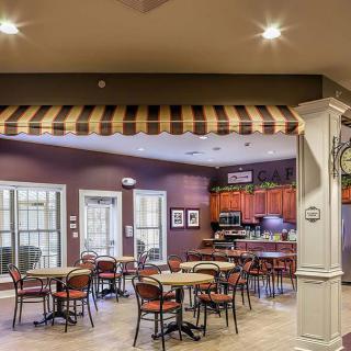 A cozy cafe interior featuring tables and chairs under a striped awning.