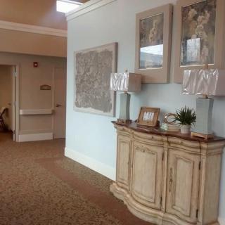 A well-decorated hallway featuring a cabinet with lamps and artwork on the walls.