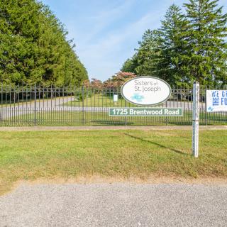 Entrance gate to a facility with surrounding trees and a sign.