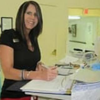A woman writing at a desk in an office setting.