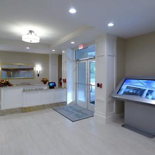 A modern lobby area with a reception desk, large digital display, and well-lit entrance.
