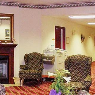 A cozy lobby area with armchairs and a fireplace, leading to a hallway.