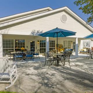An outdoor patio area with tables and chairs under blue umbrellas on a sunny day.