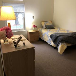 A cozy minimalist bedroom with a single bed and a well-lit lamp.