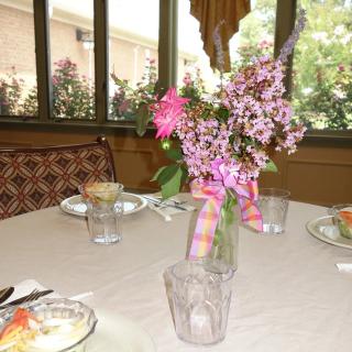 A dining table with a colorful flower arrangement in a sunlit room.