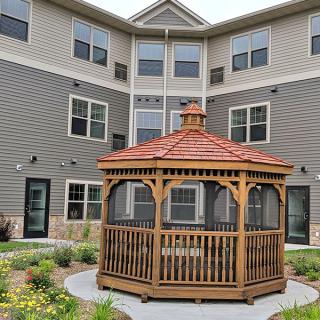 A wooden gazebo situated in the courtyard of a residential building.