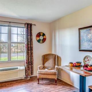 A cozy living room corner with an armchair near a window, accompanied by wall art and a decorated table.