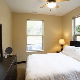 A cozy bedroom with a neatly made bed and a lamp by the window.