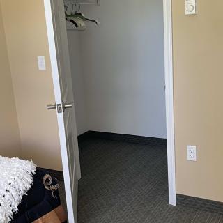 An empty room with an open closet door and hangers inside.