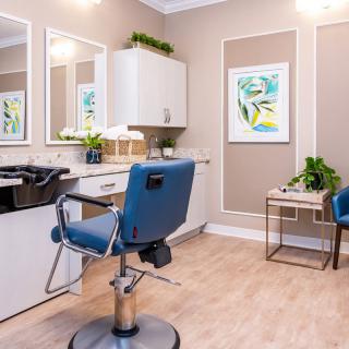 A modern hair salon interior featuring a stylish salon chair, large mirrors, and decorative plants.