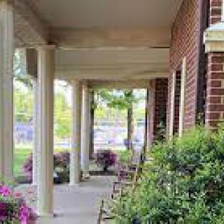 A cozy porch with columns and rocking chairs surrounded by plants.