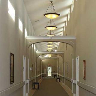A well-lit hallway with decorative light fixtures and artwork on the walls.