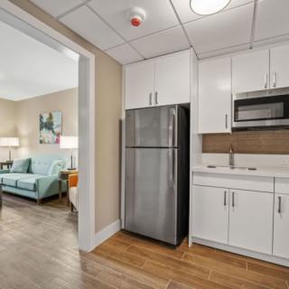Modern kitchen area in an apartment with stainless steel appliances and sleek white cabinetry.