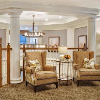 A cozy lounge area featuring two upholstered chairs, elegant lighting, and classic architectural details.