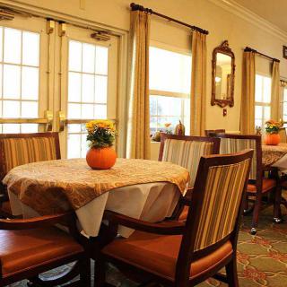 A cozy dining area with elegantly set tables and comfortable chairs, illuminated by natural light from the large windows.