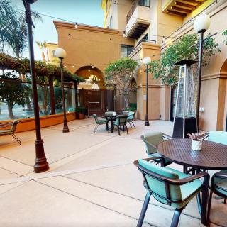 A cozy outdoor patio area with tables, chairs, and surrounding plants.