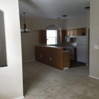 An empty kitchen area with wooden cabinets and modern appliances.