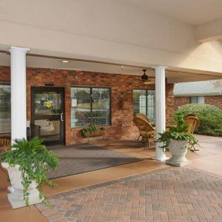 A building entrance with columns, potted plants, and a brick exterior.