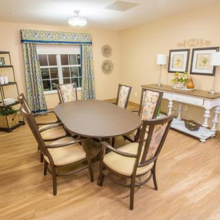 A cozy dining room with a wooden table and chairs, featuring elegant decor and hardwood flooring.
