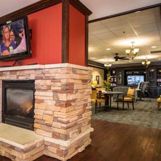 A cozy lounge area featuring a stone fireplace and a wall-mounted television, with modern decor and seating.