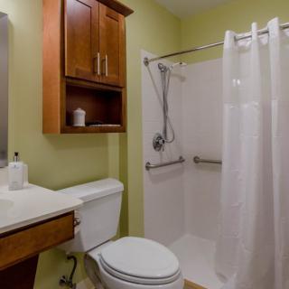 A modern bathroom with a shower, toilet, and sink featuring wooden cabinets and a shower curtain.