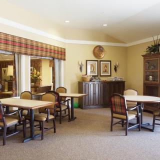 A cozy dining area with tables and chairs, featuring decorative elements such as wall art and a cabinet.
