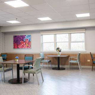 A spacious dining area featuring modern tables and chairs, complemented by vibrant artwork and ample natural light.