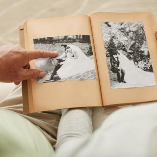 A person views a vintage photo album containing black and white wedding photographs.