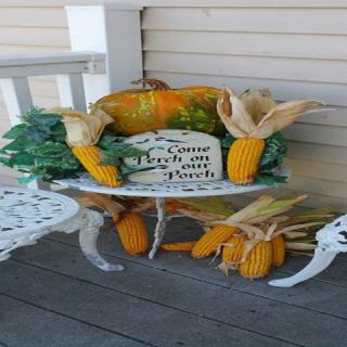 Festive autumn porch display featuring corn and gourds.