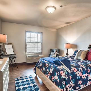 A cozy bedroom with floral bedding, warm lighting, and a patterned rug.