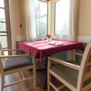 A cozy dining setup with a red tablecloth near a sunlit window.