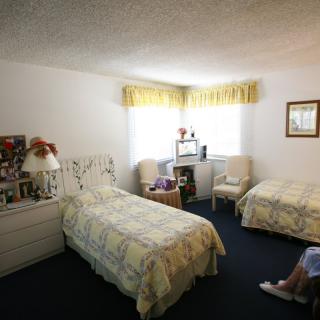 A cozy bedroom with two single beds, floral decor, and a window letting in natural light.