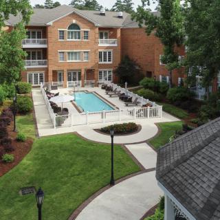 A residential apartment complex with a central outdoor pool and landscaped surroundings.