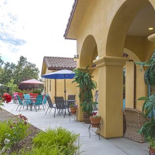 A sunny outdoor patio featuring colorful umbrellas and seating next to a yellow building.