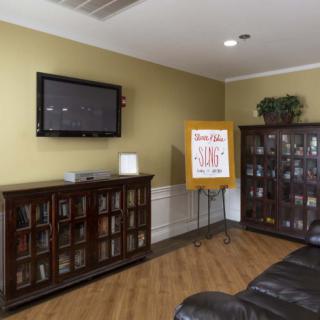 A cozy living room with a TV mounted on the wall, bookshelves, and comfortable seating.