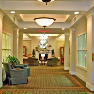 A well-lit hallway leading to a cozy seating area with sofas and a fireplace.