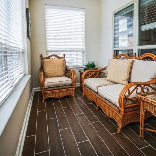 A cozy sunroom with rattan furniture and large windows.