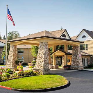 A well-maintained building entrance with stone pillars and an American flag.