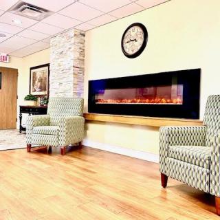 A cozy waiting area featuring comfortable armchairs and an electric fireplace.