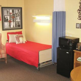 A cozy dorm room with a single bed, wall decorations, and basic kitchen amenities.