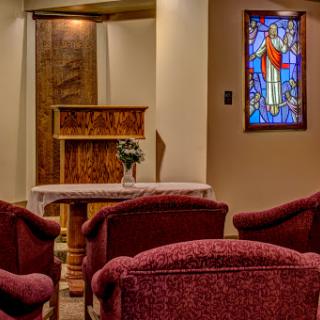 A serene interior view of a church featuring comfortable seating and a beautiful stained glass window.