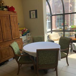 A cozy dining area with a round table and four chairs by a large sunlit window.