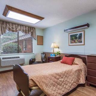 A cozy and well-lit bedroom featuring a comfortable bed, modern furniture, and a view through the window.