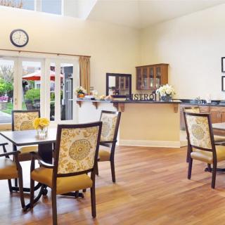 A bright and spacious dining room with wooden floors and elegant furniture, featuring large windows that allow natural light to flood in.