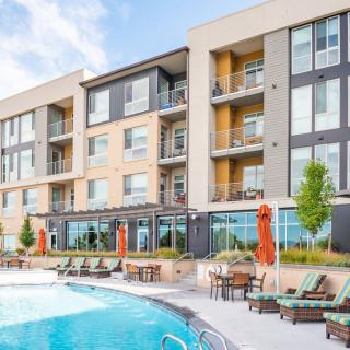A modern residential apartment building with a swimming pool and outdoor seating area.
